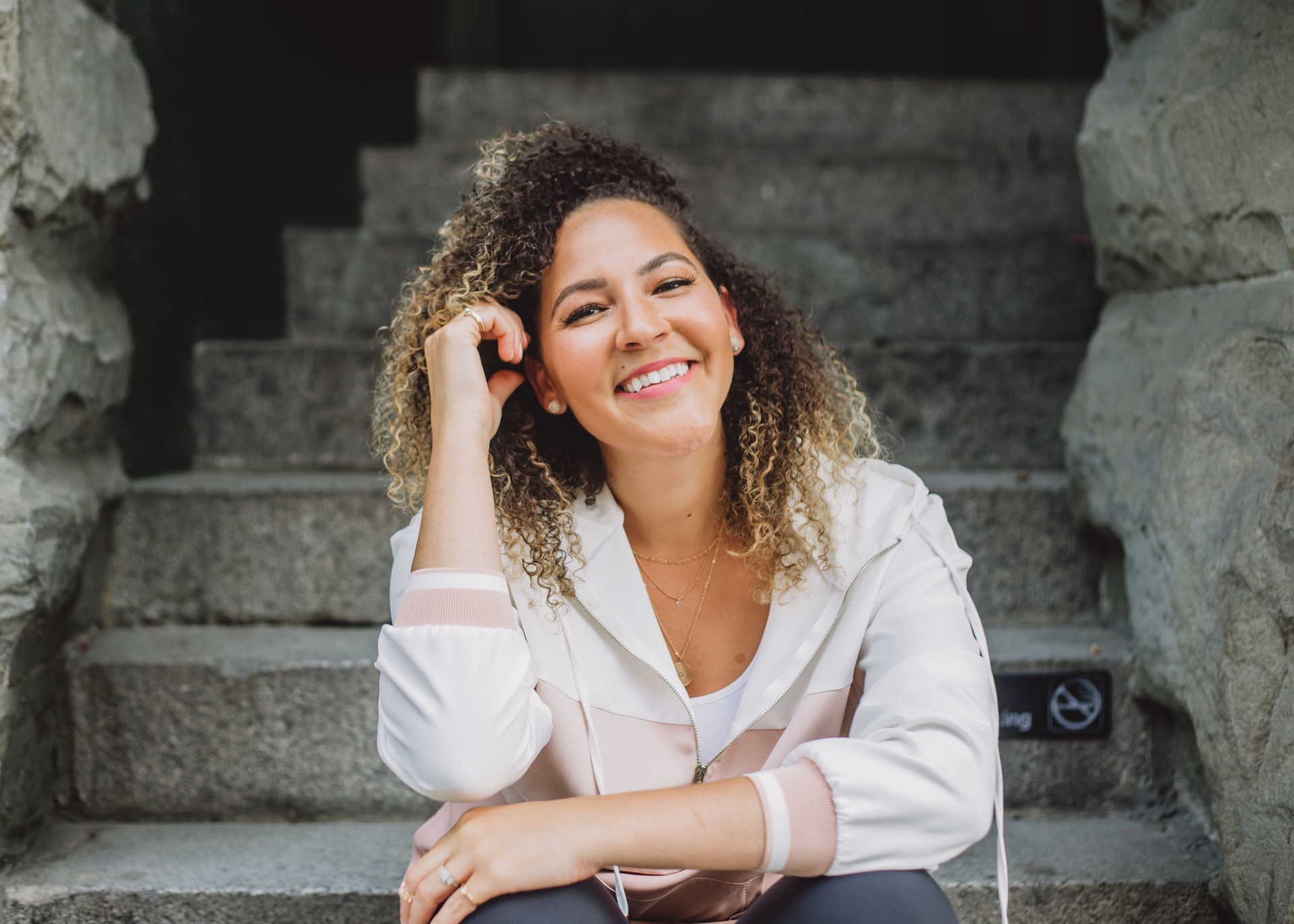 Nina Tejada, brand and presence builder, smiling on stone steps