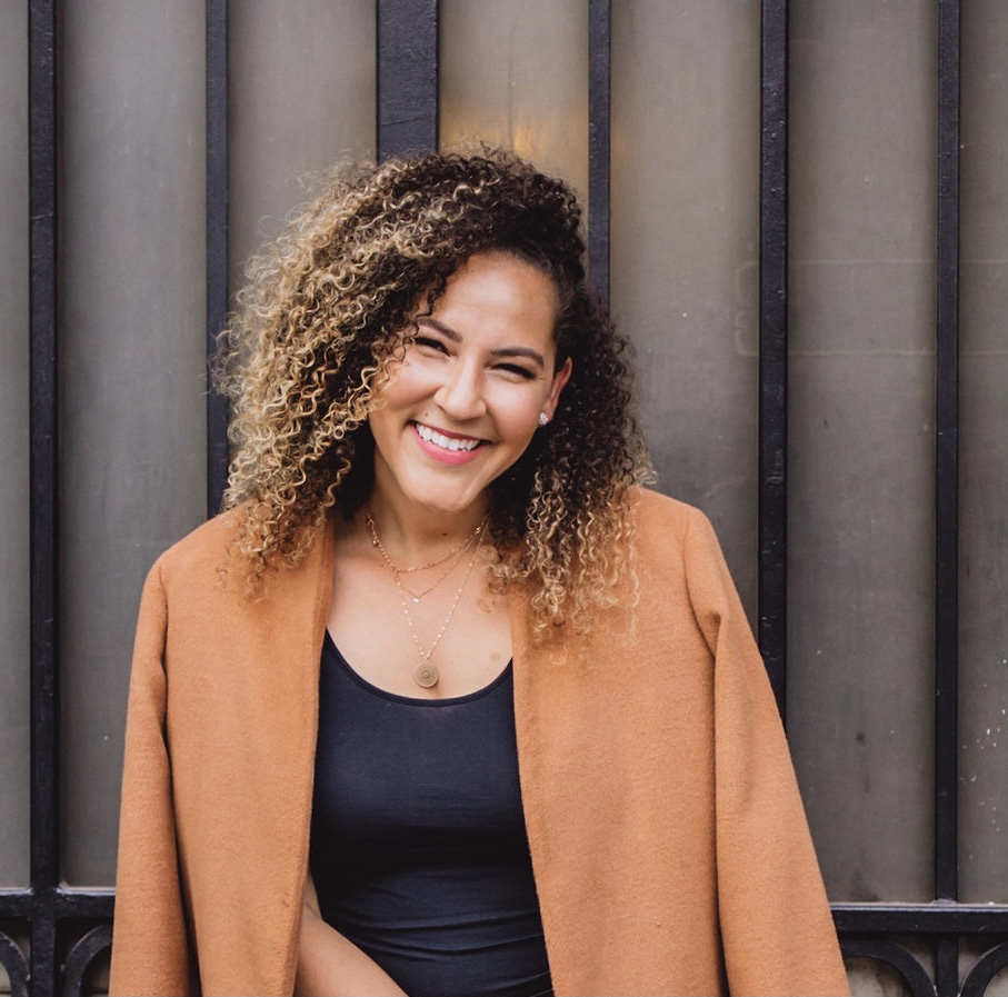 Nina Tejada, brand and presence builder for small organizations, smiling in a camel coat